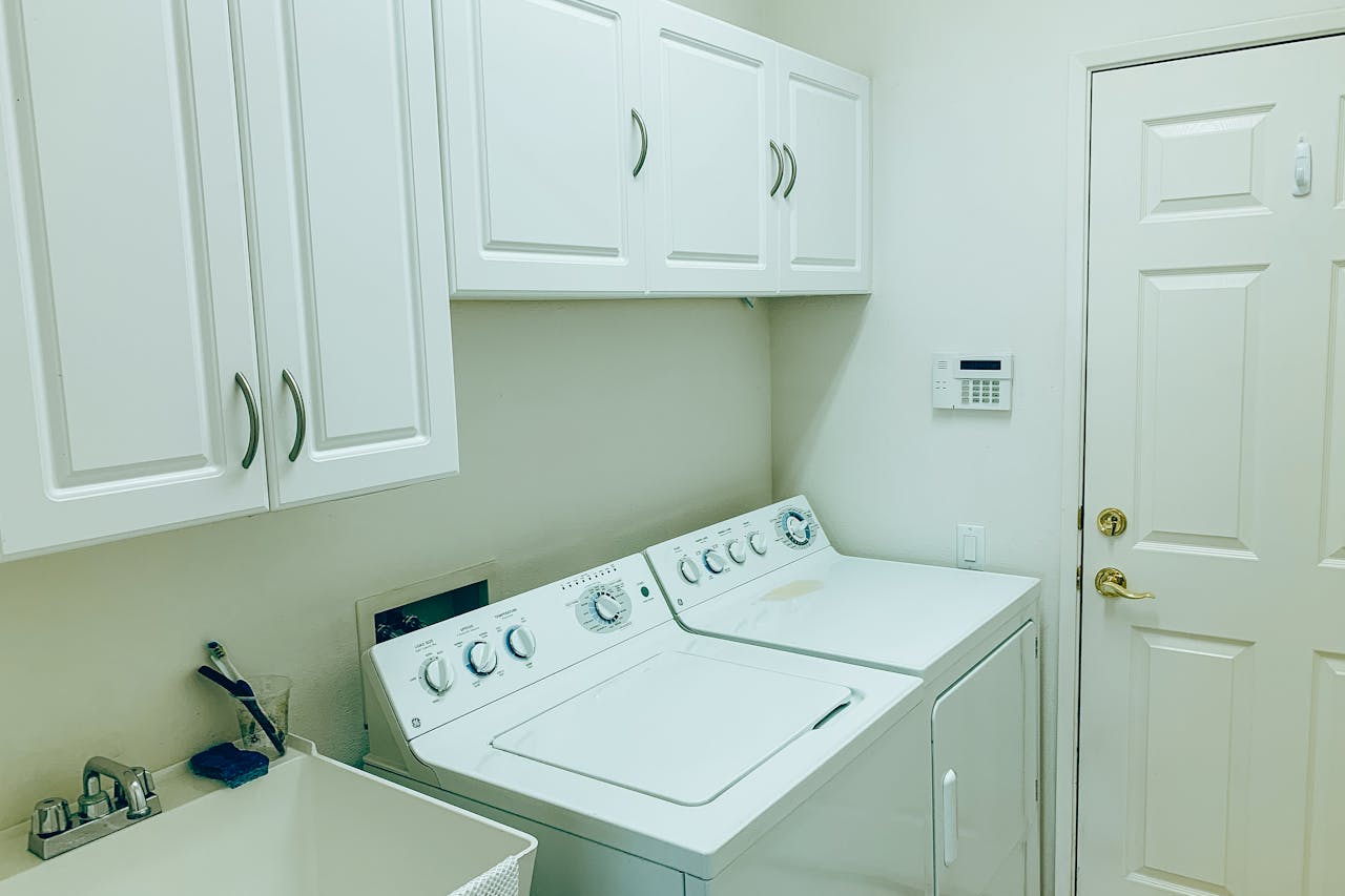 Well-organized laundry space with a washing machine, dryer, and white cabinets.